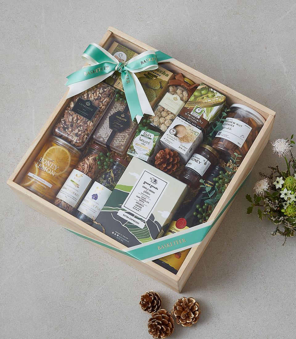 Rustic wooden gift box with gourmet honey, nuts, espresso, and natural botanicals tied with teal ribbon