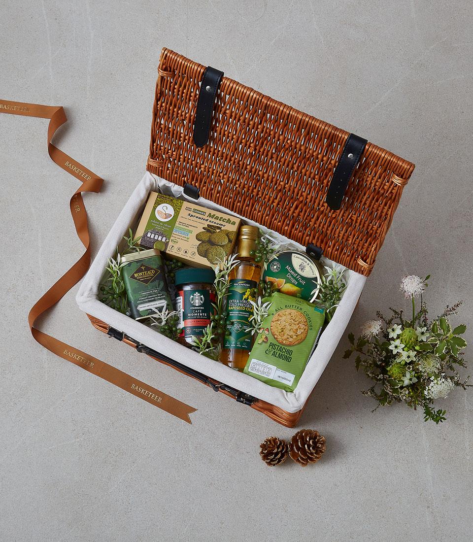 Woven wicker picnic basket with pistachio & matcha gourmet treats, tea, coffee, and artisan snacks
