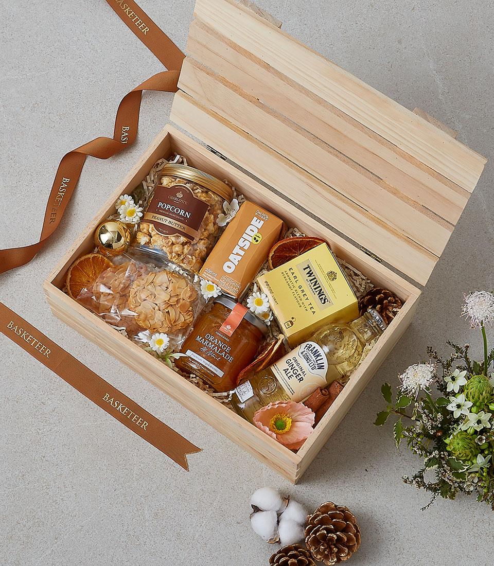 Wooden gift box with gourmet breakfast items, Earl Grey tea, oat milk, marmalade, and artisan cookies tied with brown ribbon
