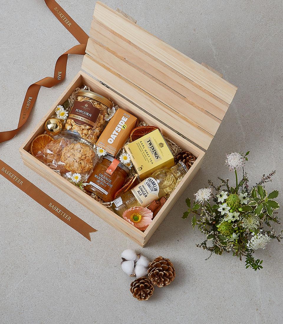 Wooden breakfast gift box with gourmet tea, marmalade, ginger ale, and artisan treats, decorated with dried citrus and white