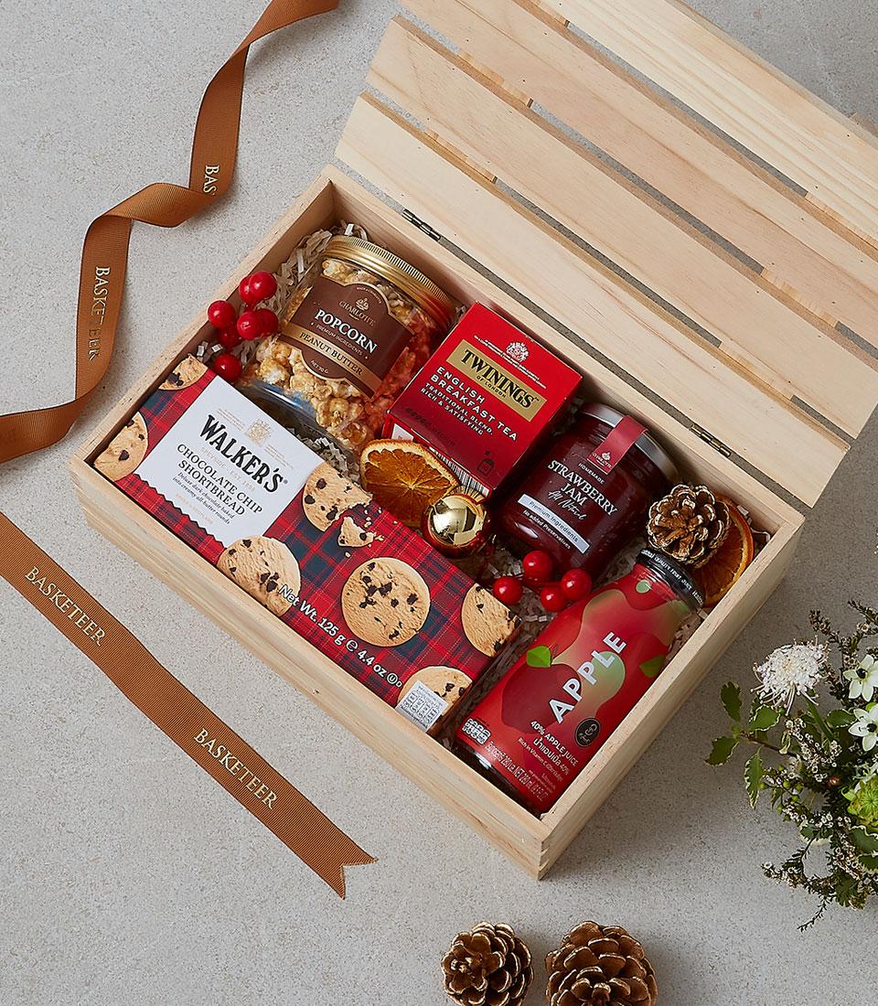 Wooden luxury gift box with gourmet treats, tea, jam, and festive red berries
