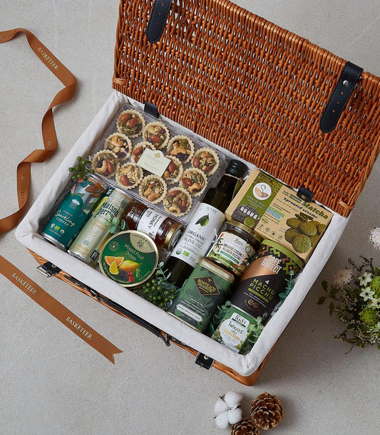 Woven wicker picnic hamper with gourmet treats, sparkling beverages, honey, olive oil, and artisan cookies