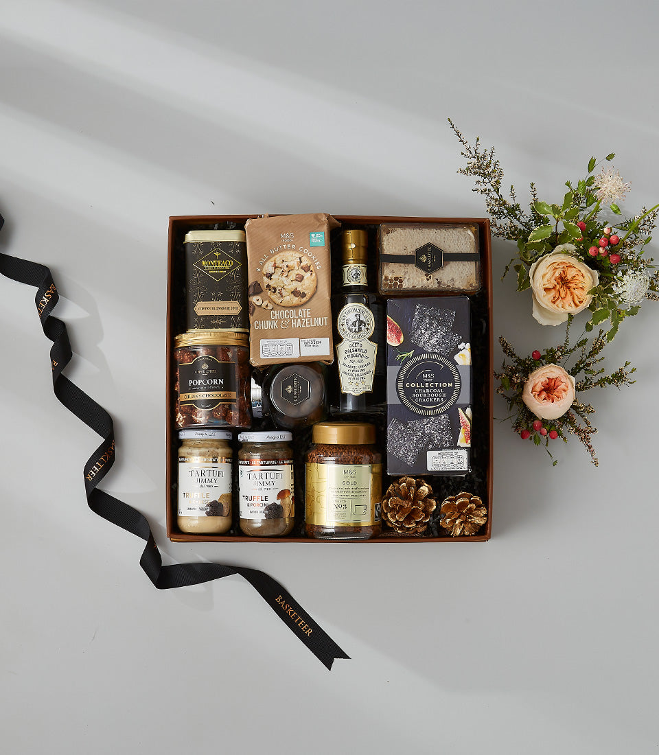 Luxury gourmet hamper with chocolate cookies, coffee, truffle spread, and artisan crackers in premium gift box