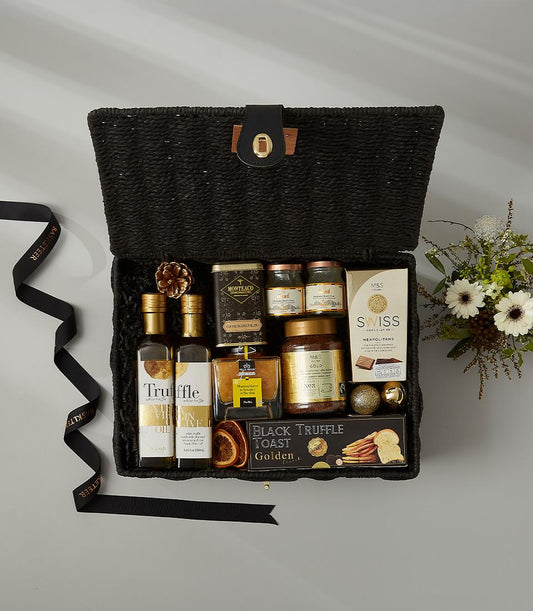 Black woven luxury gift basket with truffle oil, gourmet preserves, Swiss chocolates, and artisan crackers