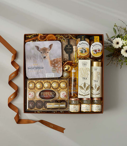 Luxury gift hamper with shortbread, Golden Earl Grey tea, honey, olive oil, chocolates, and dried citrus nestled in golden