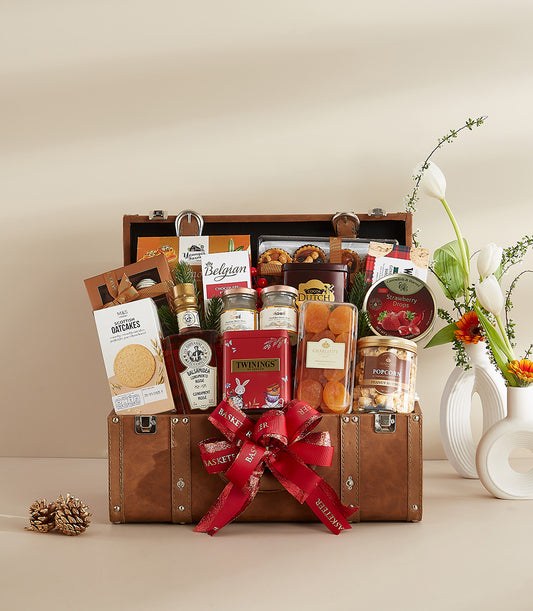 Luxury brown leather trunk hamper filled with gourmet treats, Belgian chocolate, and Scottish oatcakes, tied with red