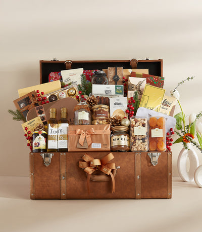 Luxe brown leather chest hamper filled with gourmet treats, truffle oil, and festive gold-wrapped gifts with fresh flowers