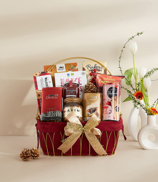 Deep red velvet gift basket with gold handle filled with gourmet treats, cocoa, jam, coffee and chocolates for New Year