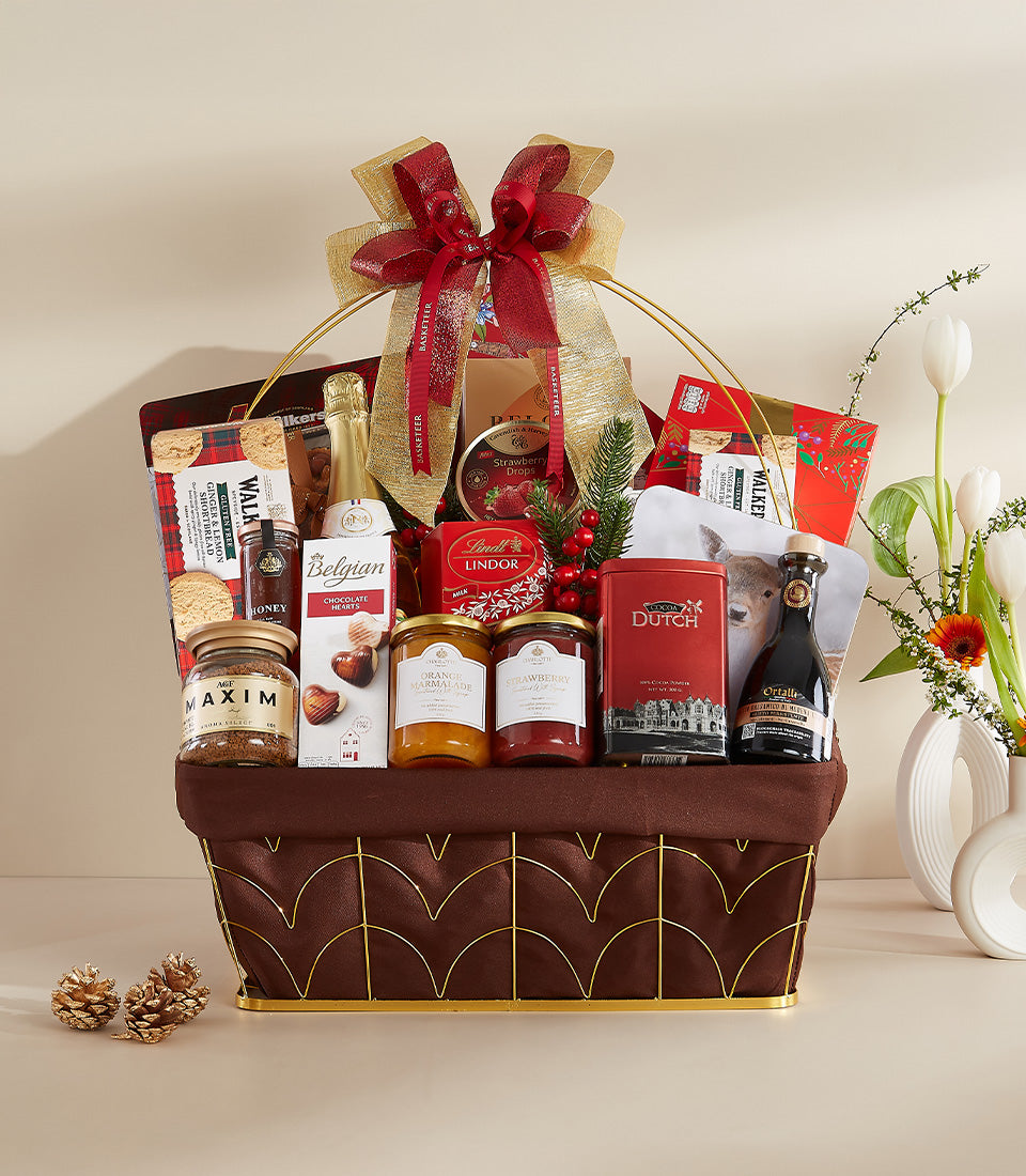 Gourmet New Year gift hamper with champagne, Belgian chocolate, coffee, and preserves in gold wire basket with red satin bow