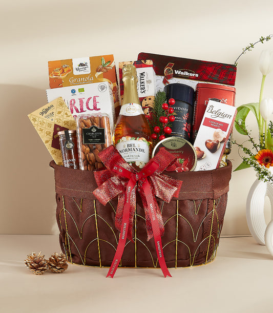 Festive gourmet gift basket with sparkling cider, chocolate, coffee, and artisan crackers tied with red ribbon