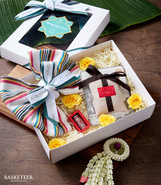 Songkran gift set with yellow roses, incense, and mango sticky rice in white presentation boxes with banana leaf