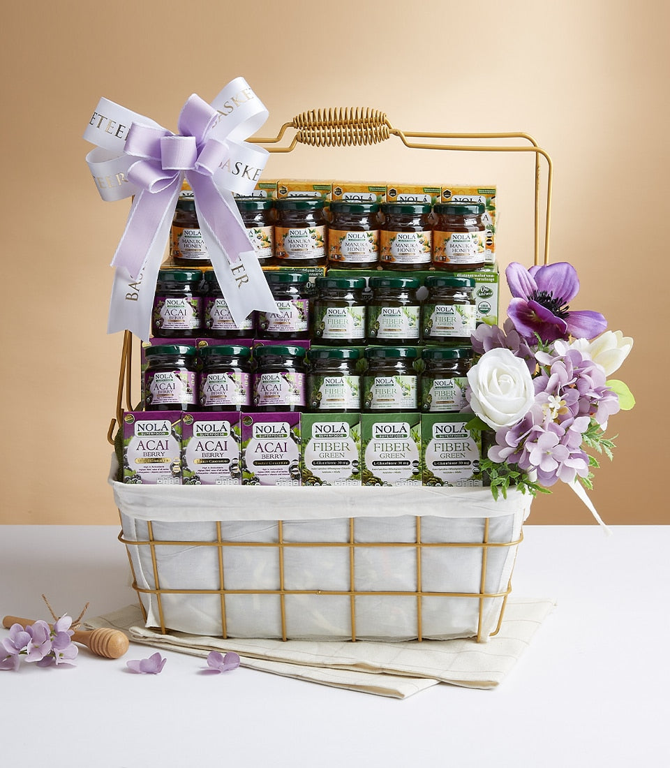 Gold wire gift basket with manuka honey, acai berry, and fiber green wellness products, tied with purple ribbon bow
