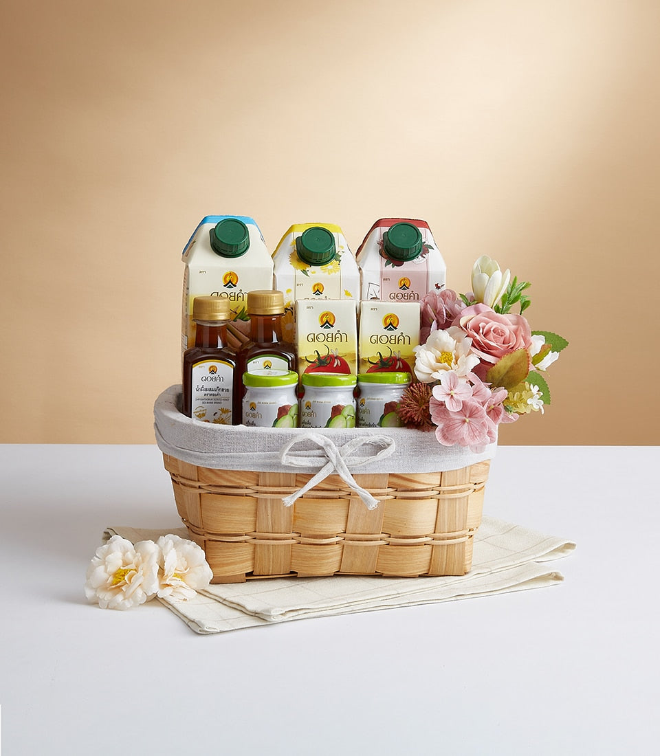 Woven gift basket with Doi Kham mixed juice boxes, honey bottles, and fruit preserves, topped with pink roses and tulips