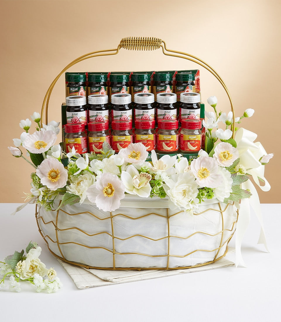 Luxury mixed delicacies gift basket with bottled gourmet items, white fabric-lined frame, and white orchid floral arrangement