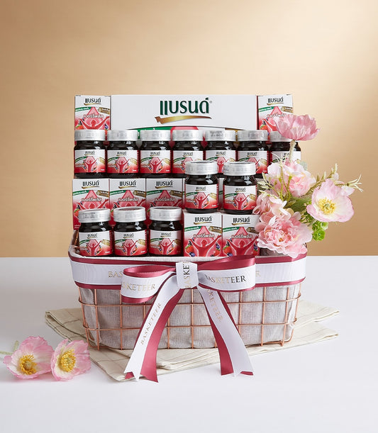 Premium rose gold gift basket with berry health drink bottles, white ribbon, and pink flowers