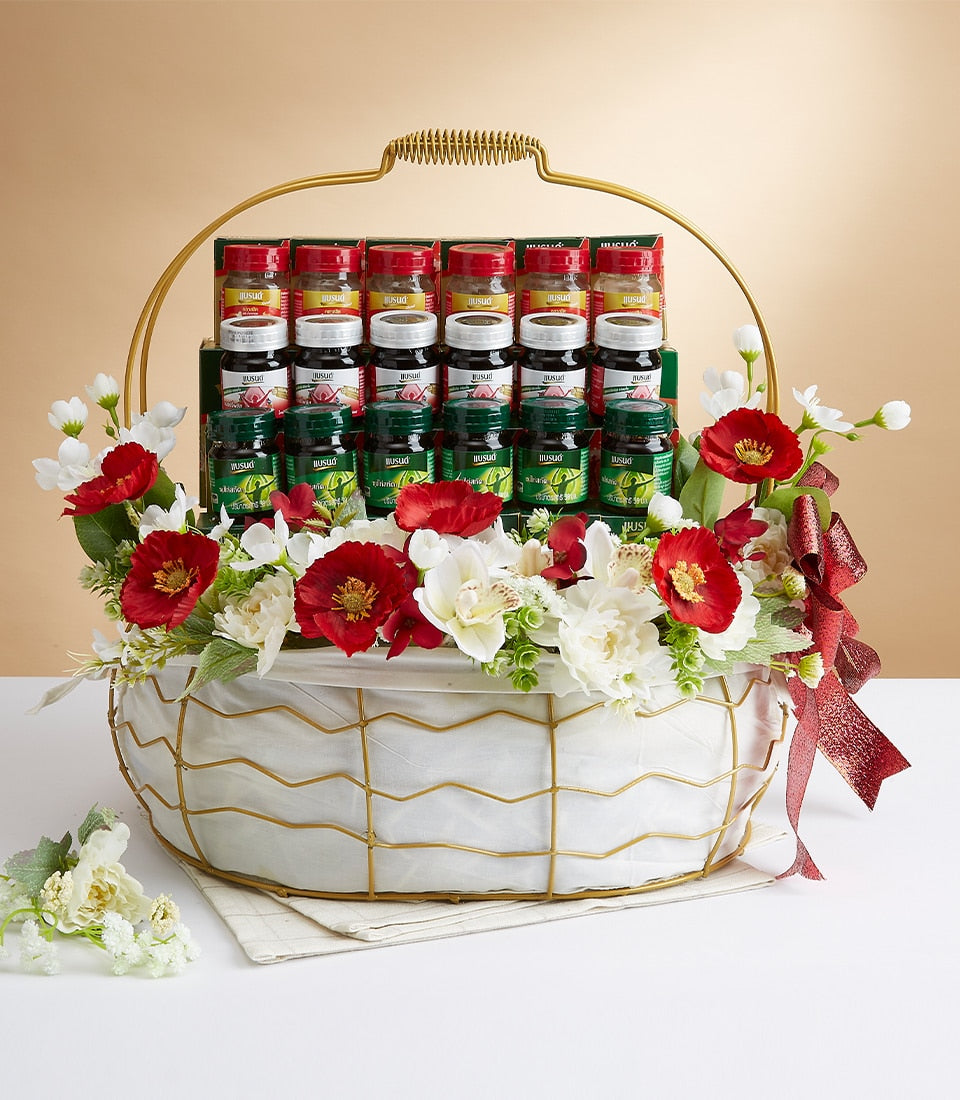 Luxury wellness gift basket with red, white, and green-capped bottles, white fabric lining, gold wire frame, and mixed red