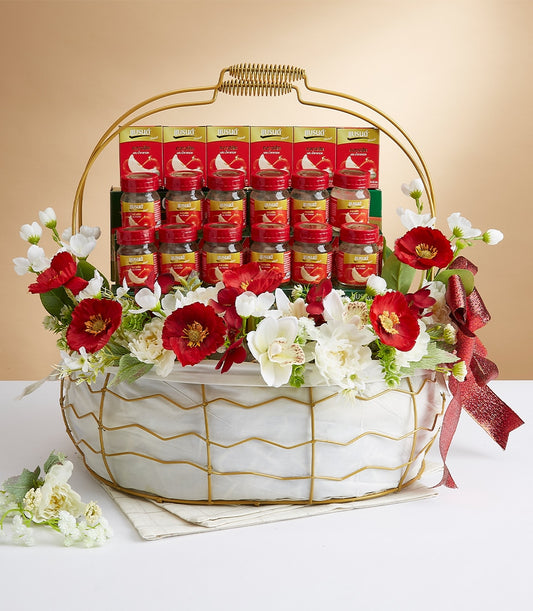 Luxe gift basket with red-lidded jars, white orchids, and red poppies in gold-handled woven frame