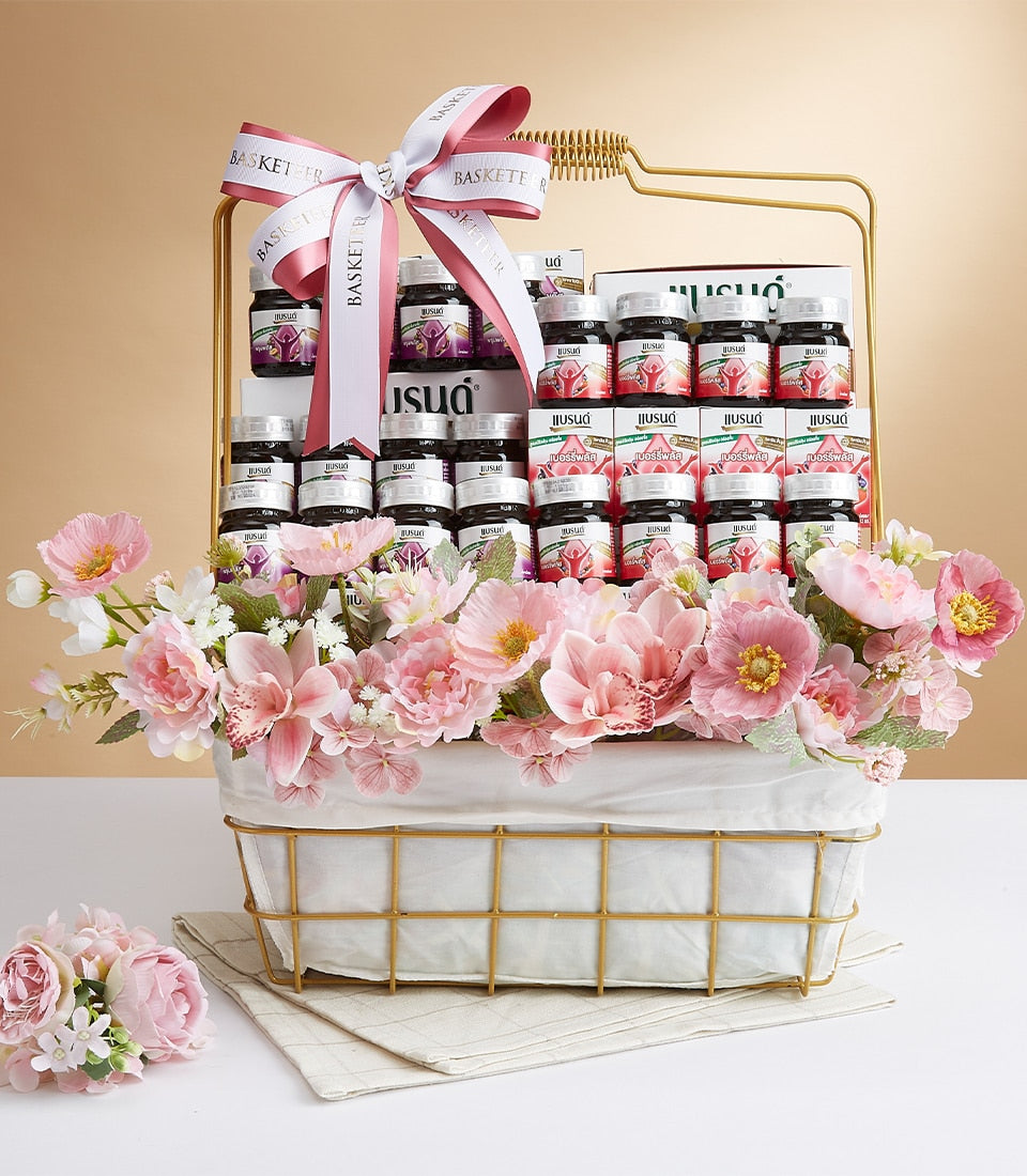 Premium gift basket with bottled beverages, pink and white artificial flowers, and golden wire design for wellness gifting
