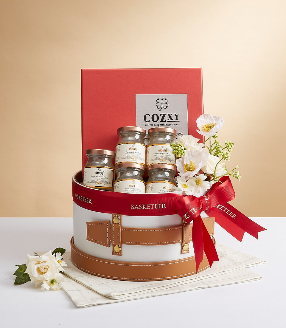 Cozxy Premium Bird's Nest Essence luxury gift set with seven glass jars, white flowers, and red satin ribbon