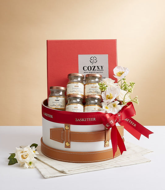 Cozxy Premium Bird's Nest Essence luxury gift set with seven glass jars, white flowers, and red satin ribbon
