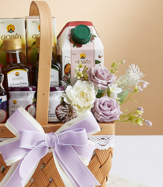 Woven gift basket with lavender bow filled with Doi Kham gourmet preserves, wellness beverages, and artisan jars