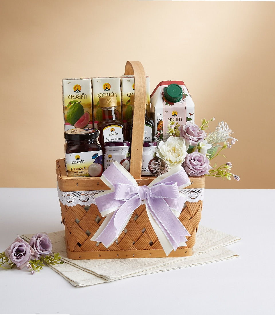 Woven gift basket with guava juice, honey, jam, and lychee-mangosteen preserves, topped with lavender and white roses