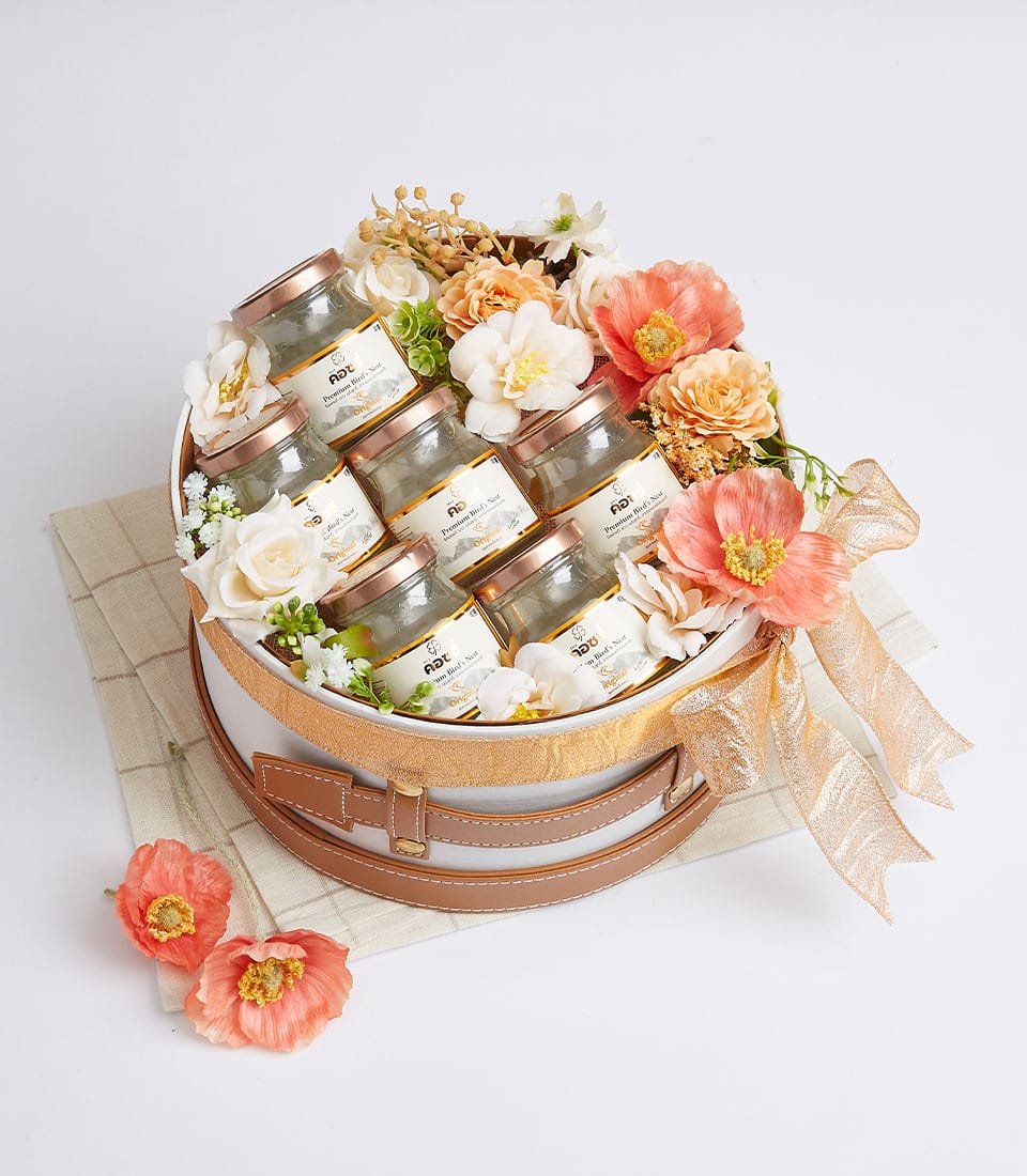 Basketeer premium hamper delivery in Bangkok. Bird's nest jars nestled in a luxurious round gift box with peach and cream flowers, tied with a gold ribbon.