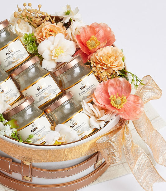 Premium bird's nest drink set in white and brown gift box with gold ribbon and peach floral arrangement