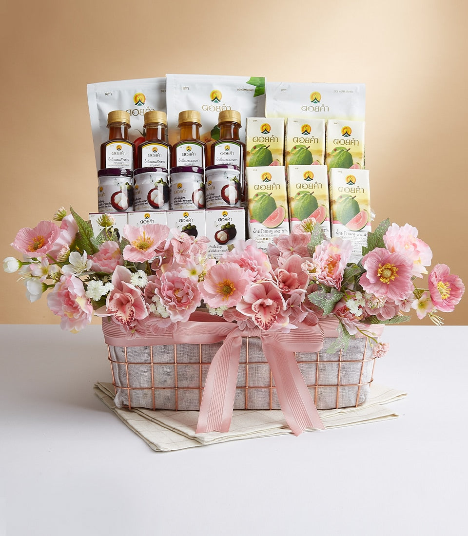 Rose gold wire mesh gift basket with bottled beverages, jars, and pink satin bow, topped with artificial pink and white