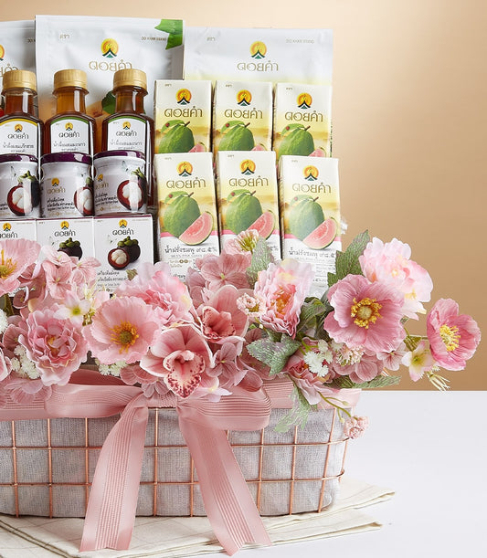 Rose gold wire mesh gift basket with Doi Kham wellness products, pink satin bow, and fresh pink floral arrangement