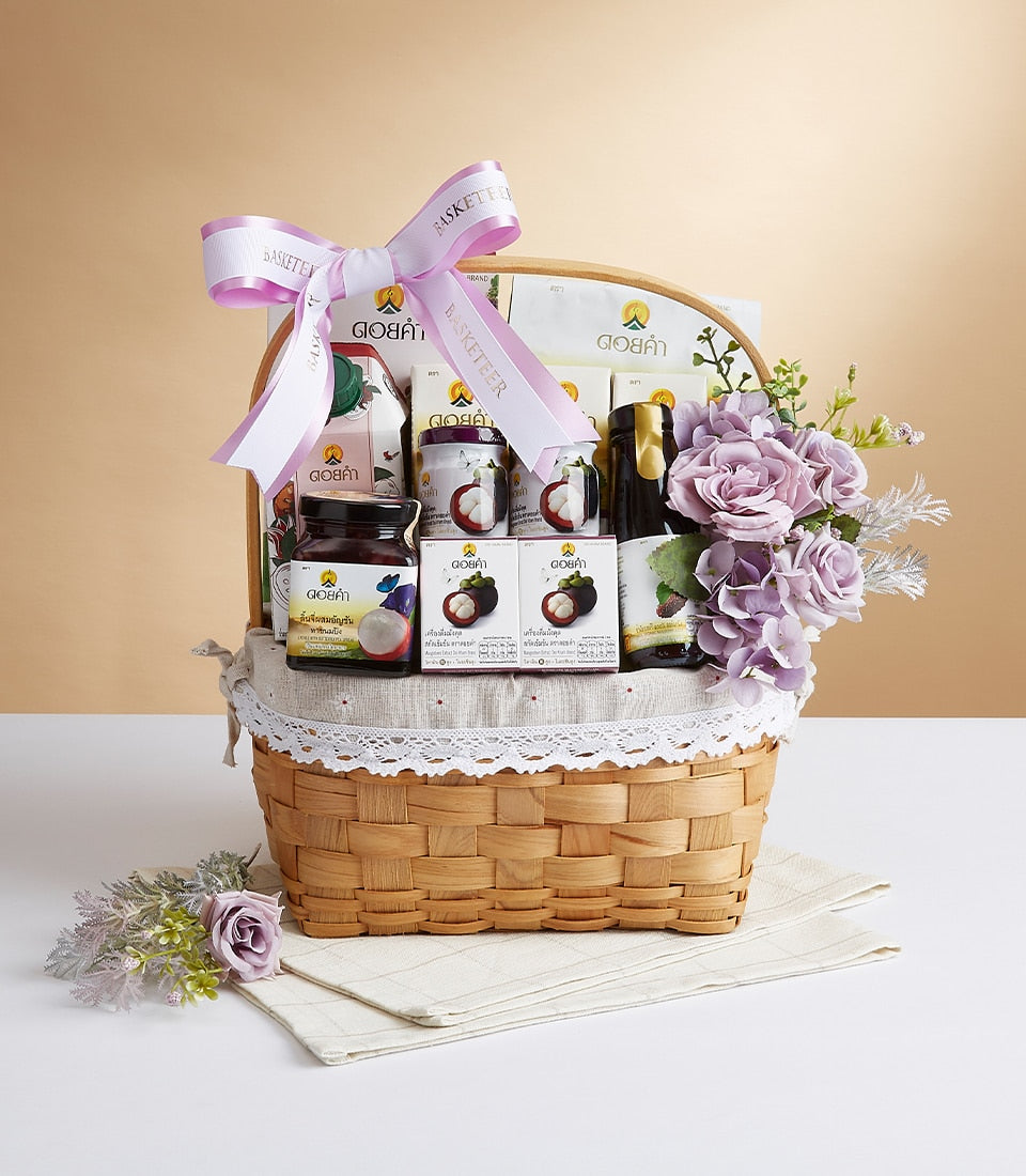 Refined Doi Kham wicker gift basket with mangosteen wellness products, purple roses, and pink Basketeer ribbon bow