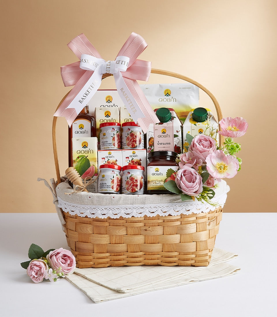 Pink luxury gift basket with premium juices, preserves, and wellness beverages in woven wood with Basketeer ribbon