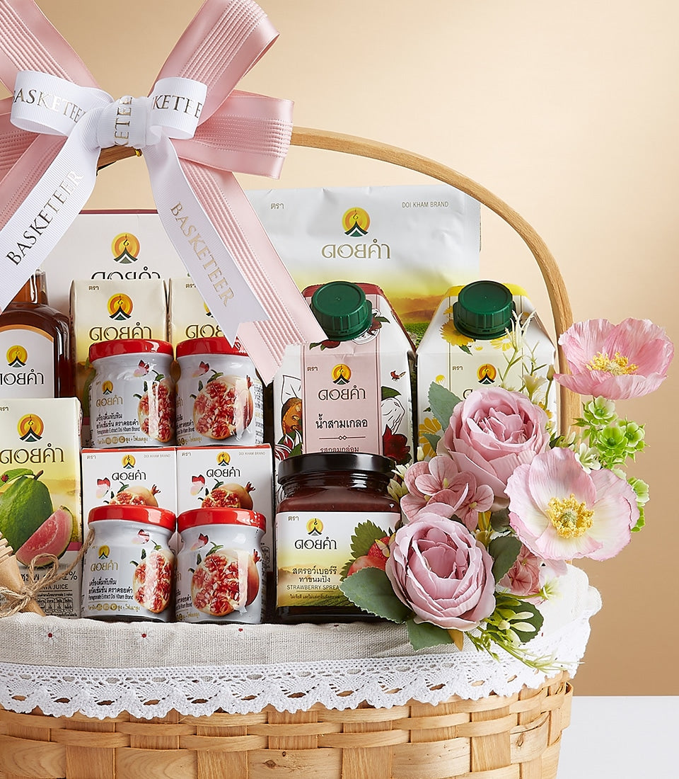 Luxury wicker gift basket with pink ribbon bow filled with gourmet health and wellness products, preserved fruits, and