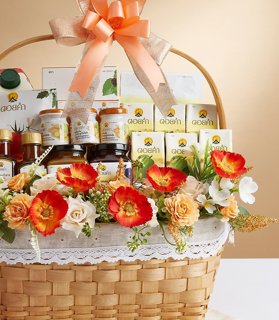 Wicker gift basket with Doi Kham gourmet products, white packaging, gold accents, red and orange flowers, grey lace trim and