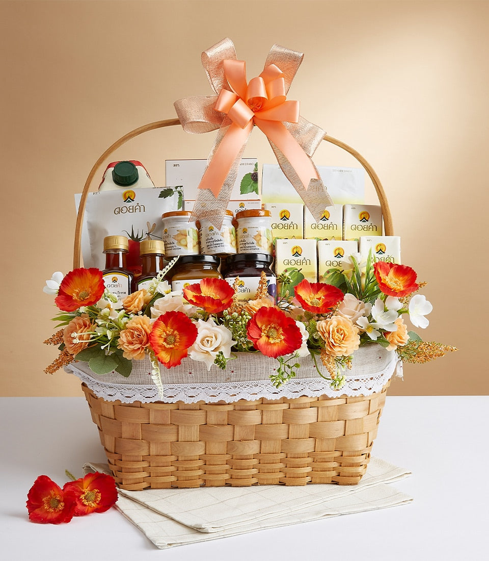 Wicker gift basket with Doi Kham gourmet assortment, honey jars, peach ribbon, and tropical flowers