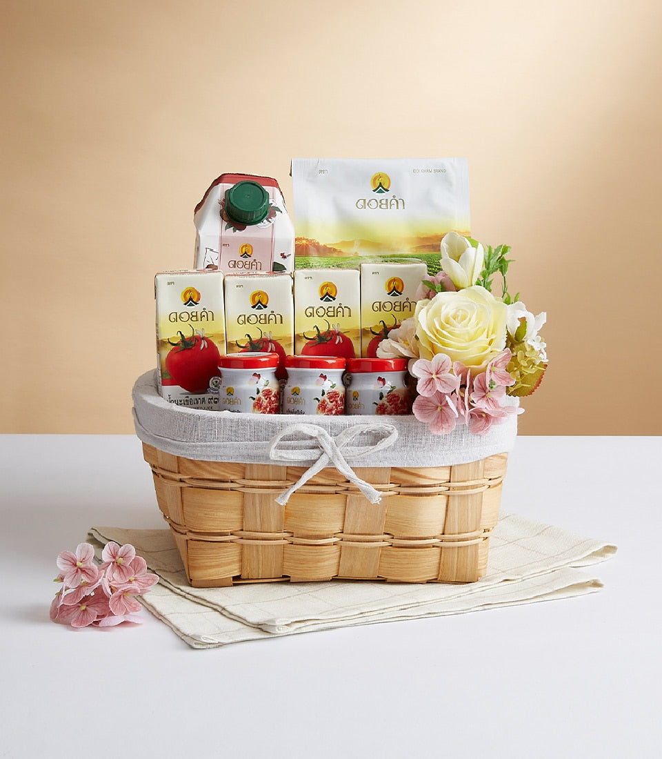 Curated wicker gift basket with Doi Kham wellness products, fresh cream roses, and white tulips