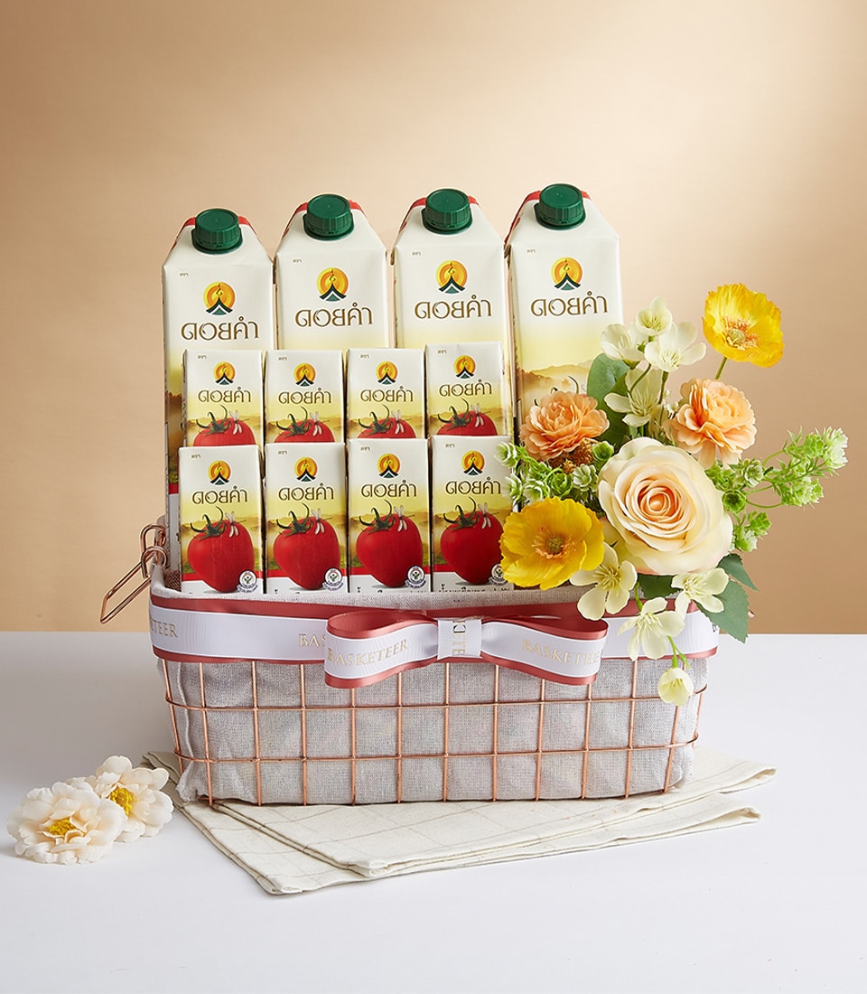 Regal Doi Kham wellness gift basket with rose gold wire frame, tomato juice cartons, and cream roses with orange poppies