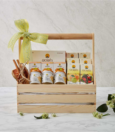 Wooden gift crate filled with Doi Kham healthy drinks, preserved fruits in glass jars, cinnamon sticks, and wellness boxes