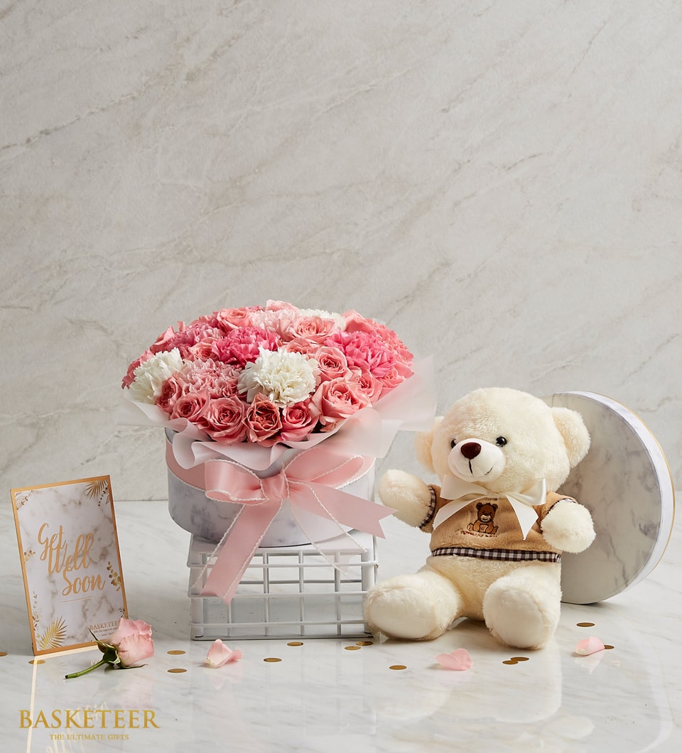 Pink roses and carnations in satin-ribboned hatbox with cream teddy bear and Get Well Soon card
