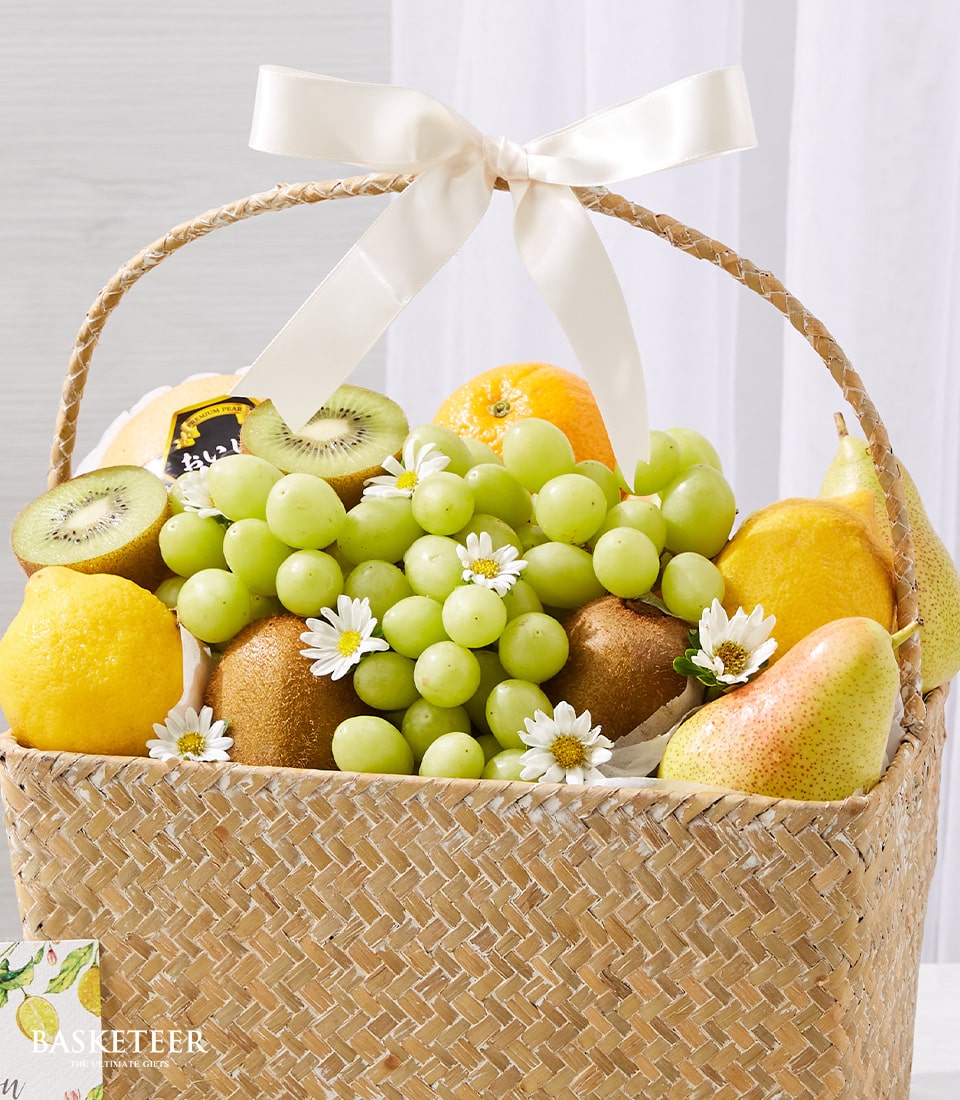 Premium woven fruit basket with fresh grapes, kiwis, lemons, pears, and orange, cream satin bow