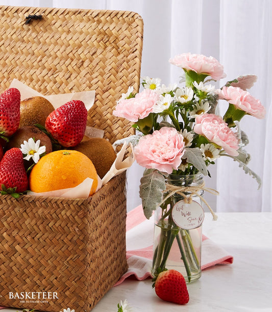Fresh fruit wellness basket with strawberries, kiwis, oranges and pink carnation flowers for get well recovery