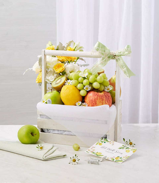 Wellness fruit basket with fresh apples, grapes, kiwi, yellow roses and white daisies in white wooden crate, get well gift