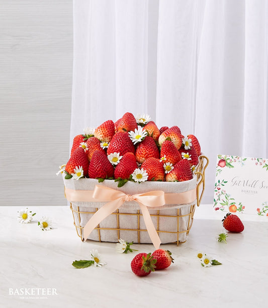 Fresh red strawberries with white daisies in gold wire basket with peach satin ribbon