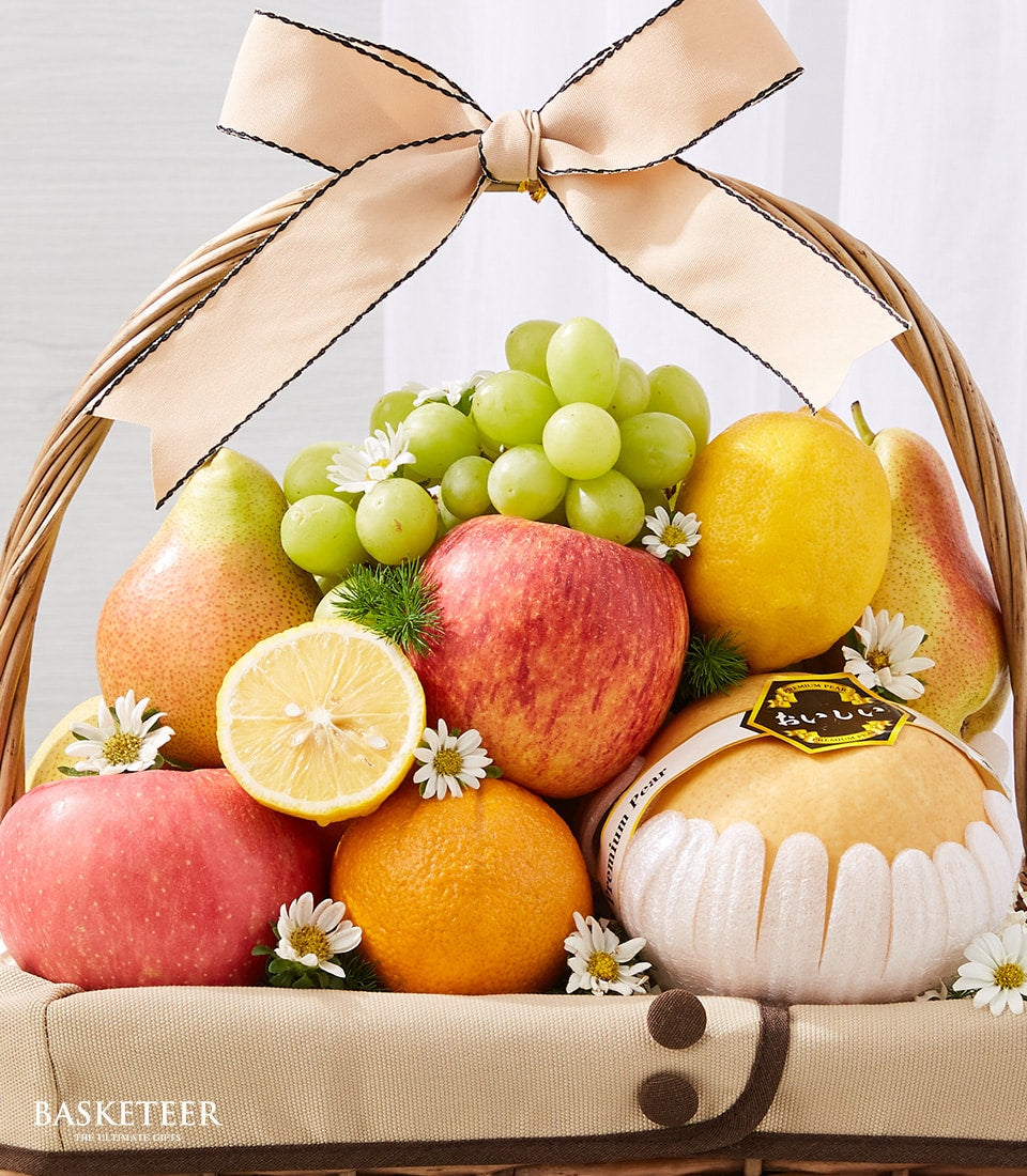 Woven wicker fruit basket with fresh green grapes, apples, lemons, tangerines, pears and white daisies