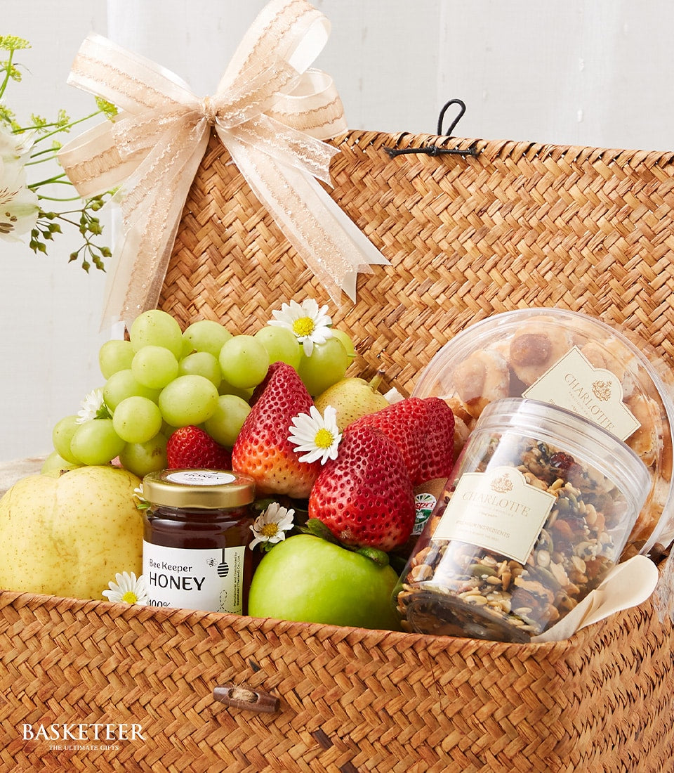 Woven wicker get well basket with fresh fruit, honey, Charlotte bakery treats, and white daisies