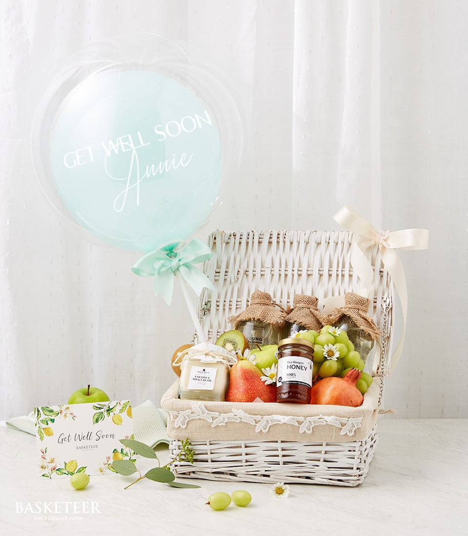 White wicker basket filled with fresh green apples, pears, kiwi, grapes, and pomegranates with honey and coconut cream jars,