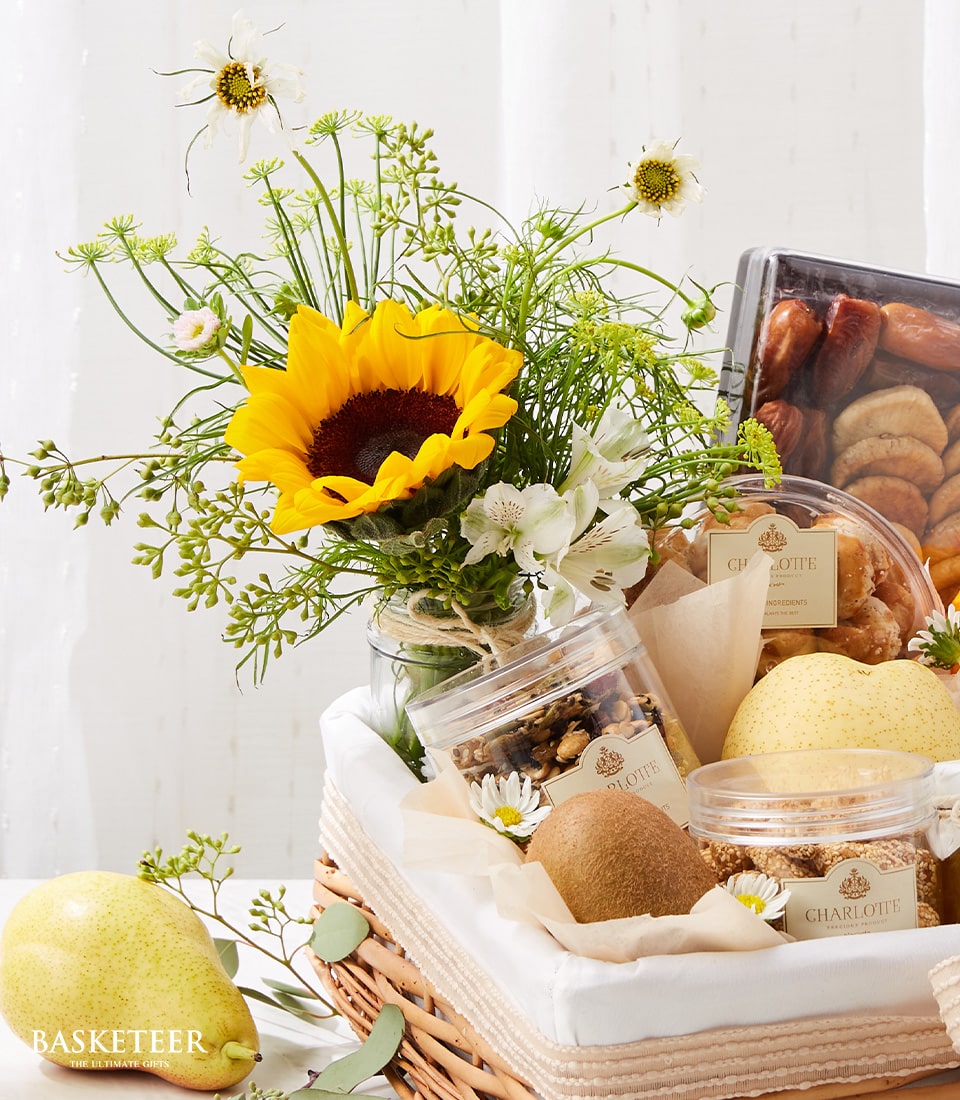 Wicker gift basket with yellow sunflower arrangement, fresh fruits, nuts, and gourmet treats for get well recovery