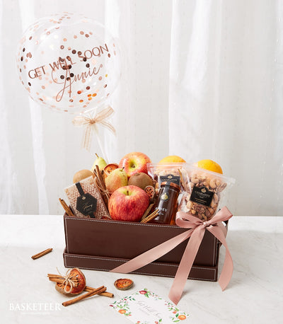 Get well soon fruit basket with apples, pears, kiwis, oranges, honey, nuts, and rose gold confetti balloon
