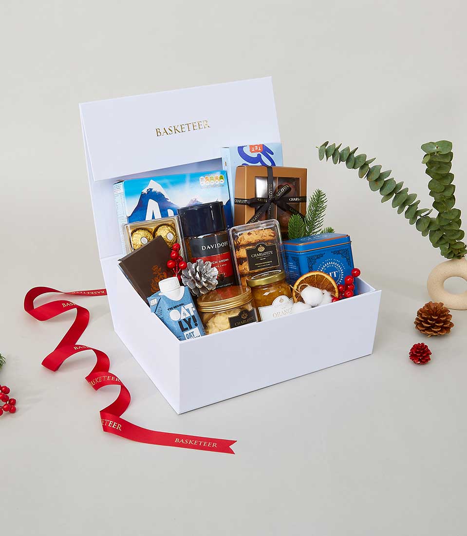 Luxurious white gift box filled with Ferrero Rocher chocolates, gourmet coffee, cookies, and preserves with festive red