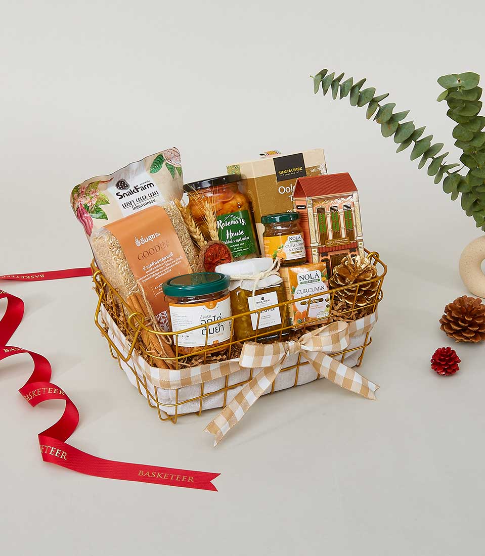 Rustic gold wire basket with gingham lining filled with gourmet jars, grains, and artisan condiments for New Year gifting